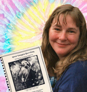 Beth smiling holding Deadhead cookbook with tiedye background