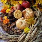 altar photo with break, flowers, apples, a candle, and stems of wheat