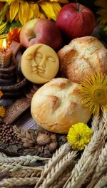 altar photo with break, flowers, apples, a candle, and stems of wheat