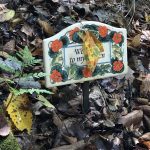 Autumn Leaf dangles on garden marker surrounded by other leaves