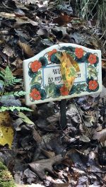 Autumn Leaf dangles on garden marker surrounded by other leaves