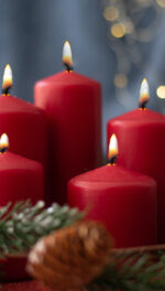 Five red candles lit with greenery and ornaments