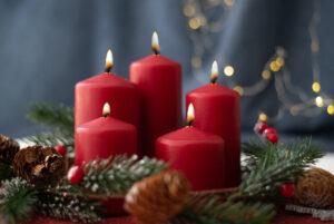 Five red candles lit with greenery and ornaments