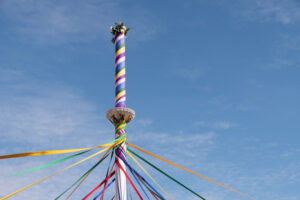 ribbons encircling around a Maypole against a bright blue sky