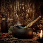 Samhain altar with pentagram sign, burning candles, dry herbs, iron cauldron, smoking mugwort, bunch of garlic