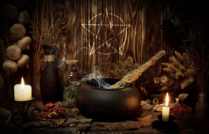 Samhain altar with pentagram sign, burning candles, dry herbs, iron cauldron, smoking mugwort, bunch of garlic