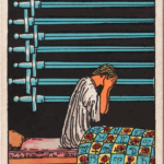 Rider Waite Smith Nine of Swords depicting figure sitting up in bed at night, face in hands with nine horizontal swords hanging in background