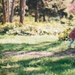 Happy baby girl laughing and playing outside. Hugging a tree. Little nature lover.