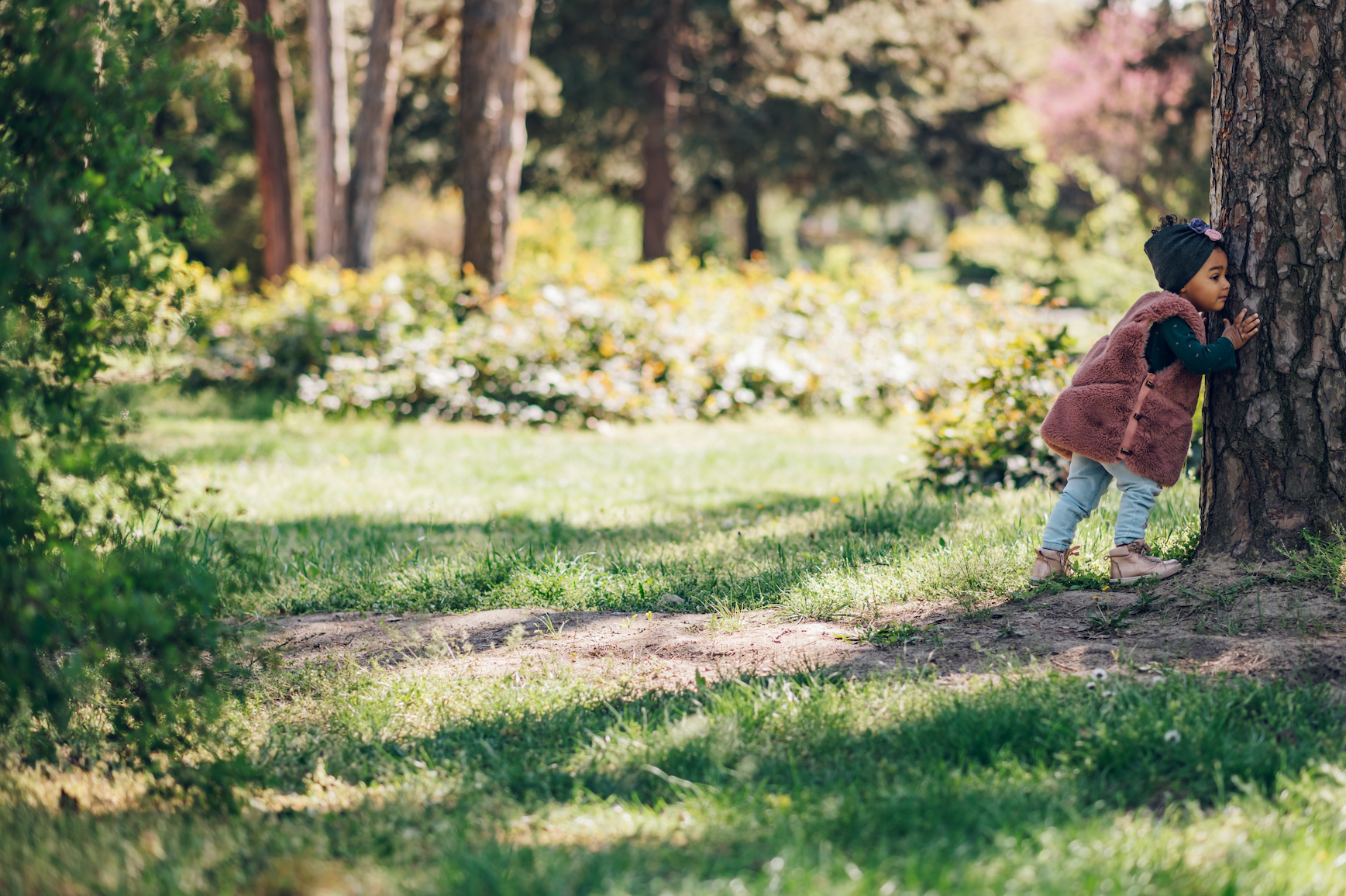 Happy baby girl laughing and playing outside. Hugging a tree. Little nature lover.