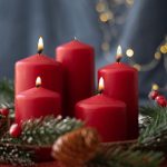 red candles, spruce branches, cones and garland on red table on blurry background.