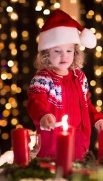 Child lighting a candle on advent wreath