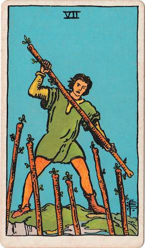 Waite-Smith Tarot Seven of Wands Young man in green tunic holding stave stands on edge of cliff prepared for battle